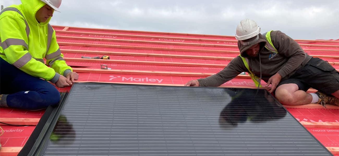 Two roofers installing solar panels onto a marley battened roof