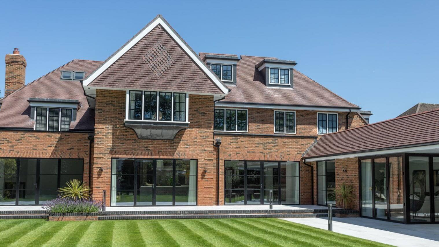 High quality residential property featuring Marley Acme Double Camber roof tile – a roof tile type often used in residential projects. The image shows this kind of roof tile’s versatility, with a complex roof including a hip roof, a gable end, dormers and roof windows.
