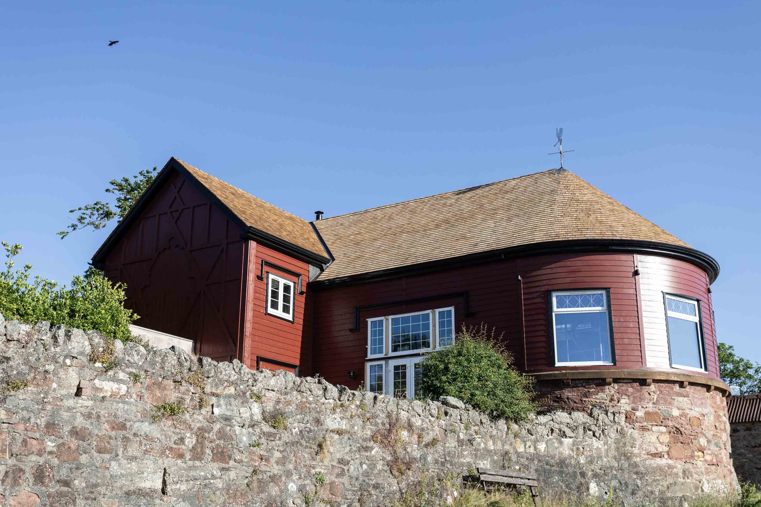 A house overlooking a cliff with a cedar shingle roof.