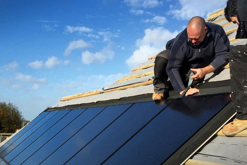 Roofer installing flashing on solar panels