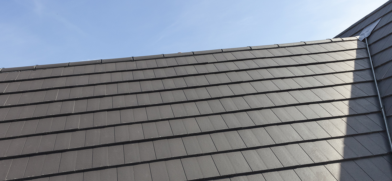 An image of a dark grey, slate tile, available from Marley slate roof specialists, in place on a roof.